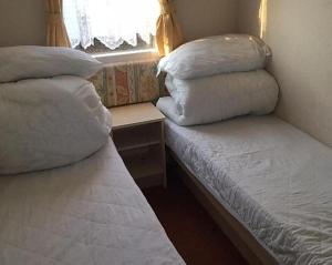 Duas camas com almofadas num quarto em Caravan Golden Palm em Chapel Saint Leonards