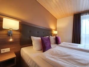 ein Hotelzimmer mit einem großen Bett mit lila Kissen in der Unterkunft Hotel in den Herrnwiesen in Wertheim