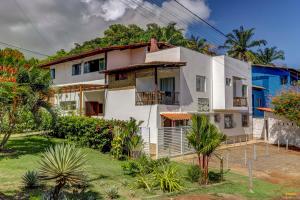 a white house with a hill in the background at Pousada Residenzial Cariocare in Itacaré