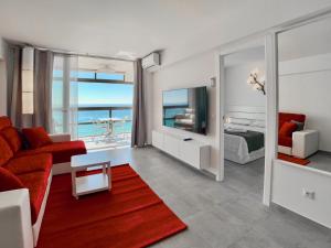 Edf CalpeMar, planta 8 - primera linea في كاليبي: غرفة معيشة مع أريكة حمراء وغرفة نوم