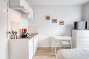 uma cozinha branca com um lavatório e uma mesa em Le Petit Magny em Magny-le-Hongre