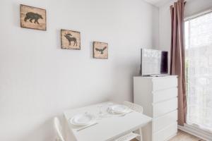 ein weißes Esszimmer mit einem Tisch und einem TV in der Unterkunft Le Petit Magny in Magny-le-Hongre