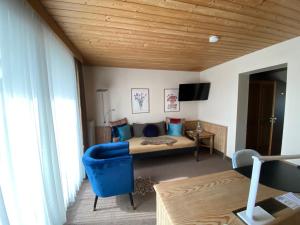 een slaapkamer met een bed met een blauwe stoel en een televisie bij Hotel in den Herrnwiesen in Wertheim