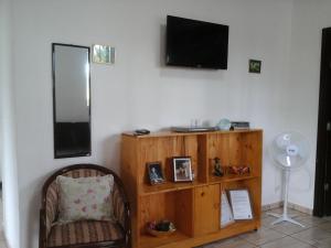 a living room with a chair and a television on the wall at Villa Maria DA Luz ROCHA Olimpia in Olímpia