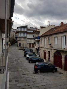 uma fila de carros estacionados numa rua com edifícios em A casa de Mateo em Ribadavia