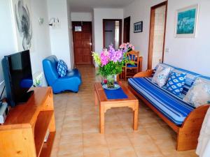 a living room with a couch and a table with flowers at Apartamentos Villa Margarita in Cala Millor