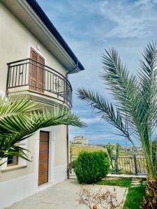 a white house with a balcony and a palm tree at Villa Torre degli Ulivi in Corigliano Calabro