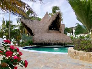 a resort with a swimming pool with a thatch roof at Cabañas Aqua Blue in Coveñas