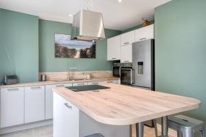 a kitchen with white cabinets and a wooden counter top at Maison Les Burons in Le Bois-Plage-en-Ré