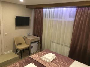 a hotel room with a bed and a desk and a television at Vesta Guest House in Kislovodsk