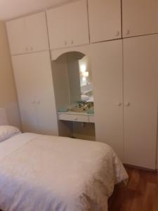 um quarto com uma cama, armários brancos e um lavatório. em Joan B+B em Clonakilty