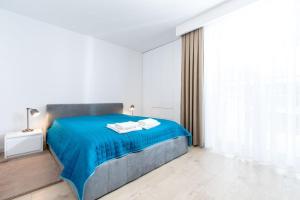 a bedroom with a blue bed with a blue blanket at Resort Apartamenty Klifowa Rewal 30 in Rewal
