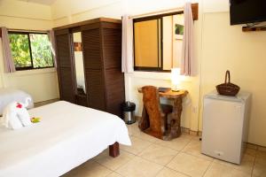 a bedroom with two beds and a table and a television at Jungle Lodge at Wild Sun Rescue Center in Cabuya