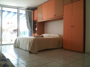 a bedroom with a bed with orange cabinets and a large window at Monolocale Rosburgo 2 in Roseto degli Abruzzi