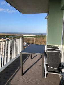 a table and chairs on a balcony with the beach at FeWo am Meer Schillig-Nordsee 47.4.M in Wangerland