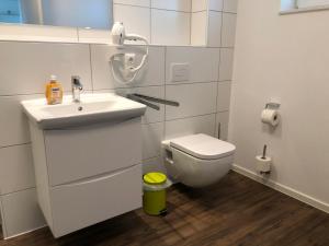 a white bathroom with a sink and a toilet at FeWo am Meer Schillig-Nordsee 47.4.M in Wangerland +10 photos