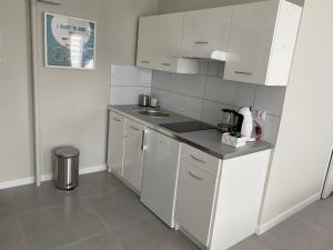 a small kitchen with white cabinets and a sink at APARTAMENT OŚ. BŁĘKITNE 10H in Dzierżoniów