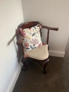 a chair with a pillow sitting in a room at The Firs at Hay-on-Wye B&B in Hay-on-Wye