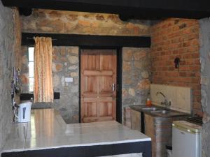 a kitchen with a wooden door and a stone wall at Madrugada in Umtali