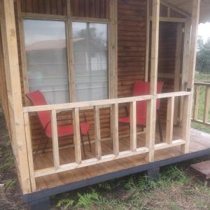 a screened in porch of a cabin with red chairs at Casa de leña, cabaña rural in Villa de Leyva