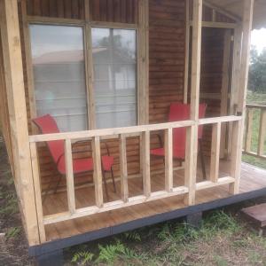 a screened in porch of a cabin with red chairs at Casa de Leña - Cabaña Rural in Villa de Leyva