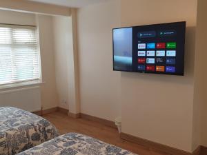 TV de pantalla plana en la pared de un dormitorio en London Luxury 3 Bedroom Flat 1min walk from Underground, with FREE PARKING Sleeps x10, en Londres