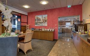um restaurante com mesa e cadeiras e paredes vermelhas em Hotel Merkur em Landstuhl