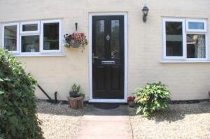 a black door on a house with two windows at 9 Bromleys Court in Church Stretton