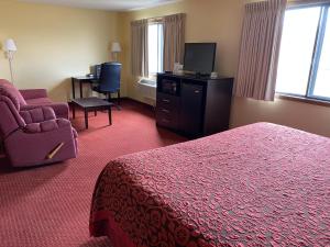 德梅因的住宿－得梅因機場戴斯套房酒店，酒店客房配有一张床、一把椅子和一台电视。