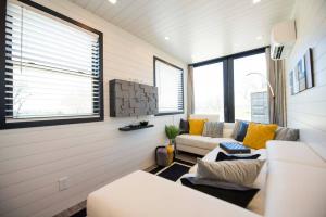 - un salon avec un canapé, des chaises et des fenêtres dans l'établissement The Zephyr Modern Luxe Container Home, à Bellmead