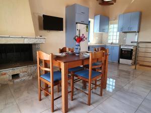 a kitchen with a wooden table with chairs and a fireplace at Stoupa Lefktro 4 in Stoupa