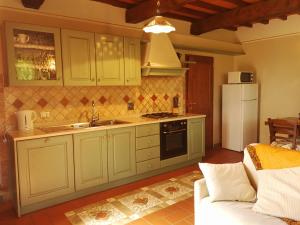 cocina con armarios verdes y nevera blanca en Residence il Poggiolino, en Montecarelli