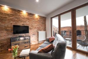 a living room with a couch and a brick wall at Rakowicka Top Apartaments Superior in Krakow