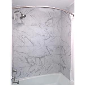 a shower with white marble walls and a white tub at Gateway Inn Savannah in Savannah