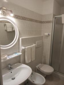 ein Badezimmer mit einem Waschbecken, einem WC und einem Spiegel in der Unterkunft Albergo Lucia in Tesero