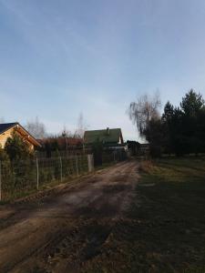 a dirt road in front of a house with a fence at Domek letniskowy - Świętne nad jeziorem Wilczyńskim in Wilczyn