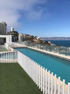 a white fence next to a body of water at Departamento Terrazas de Cochoa 2 dormitorios in Viña del Mar