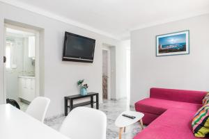 a living room with a red couch and a tv at MalagaOnBeach 2 - Two bedrooms - up to 7 people - 30 meters beach in Málaga