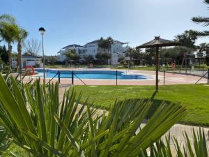 - une piscine avec un parasol dans un parc dans l'établissement Apartamento en Bahia Golf - Costa Ballena, à Costa Ballena