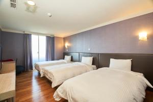 a hotel room with three beds with white sheets at HengChang Business Hotel in Keelung