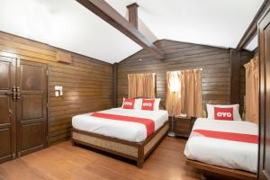 two beds in a room with wooden walls at OYO 635 Sira Boutique Hotel in Chiang Mai