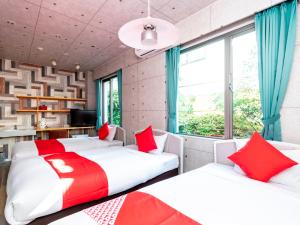 two beds in a room with red and white at Asuka Hotel in Karatsu
