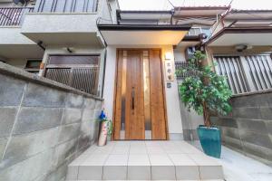 une porte en bois d'une maison avec une plante en pot dans l'établissement Kyorakuya, à Kyoto