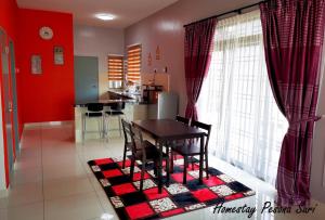 Pesona Suri Homestay في باتو باهات: غرفة طعام ومطبخ بجدران حمراء وطاولة