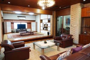 a living room with leather furniture and a television at THE TORII in Kumamoto