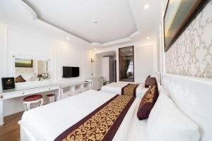 Habitación blanca con 2 camas y TV. en Mai Vang Hotel, en Da Lat