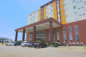 a large building with cars parked in a parking lot at Liberta Hotel Grand Sayang Makassar in Makassar