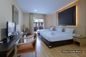 a bedroom with two beds and a desk with a television at Mutiara Suites in Jakarta