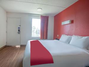 - un grand lit dans une chambre dotée d'un mur rouge dans l'établissement OYO Hotel Lake Park/Valdosta I-75, à Lake Park