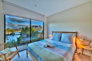 a bedroom with a bed and a large window at Furneaux in Coles Bay